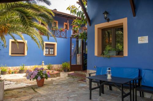 ein blaues Haus mit einem Tisch und einer blauen Wand in der Unterkunft Apartamentos y Habitaciones Casa Bego in Valdredo