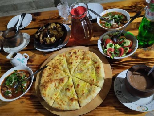 a wooden table with a pizza and bowls of food at Martvili canyon cottage in Gachedili