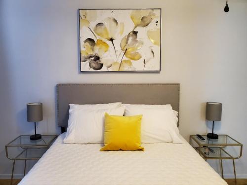 a yellow pillow sits on a bed with two tables at Condo Near Downtown Austin - 2br in Austin