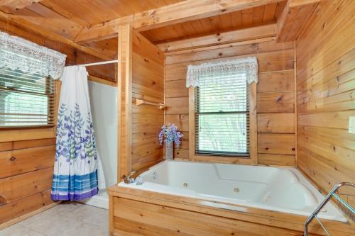 a bathroom with a large tub in a room with wooden walls at Cabin with Hot Tub about 6 Mi to Downtown Gatlinburg! in Gatlinburg