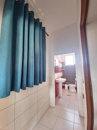 baño con cortinas de ducha azules y lavamanos en Villa Malaj, en Vlorë