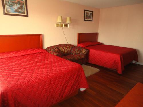 a hotel room with two beds and a chair and a couch at Niagara Lodge & Suites in Niagara Falls