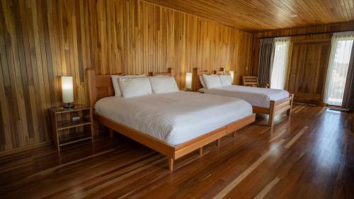 two beds in a room with wooden walls and wood floors at Fondavela Hotel in Monteverde Costa Rica