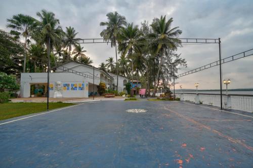 an empty parking lot with a building and palm trees at Blu Missel By The River in Panaji