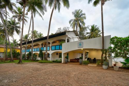 a building with palm trees in front of it at Blu Missel By The River in Panaji