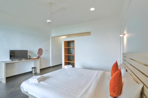 a white bedroom with a bed and a desk at Blu Missel By The River in Panaji