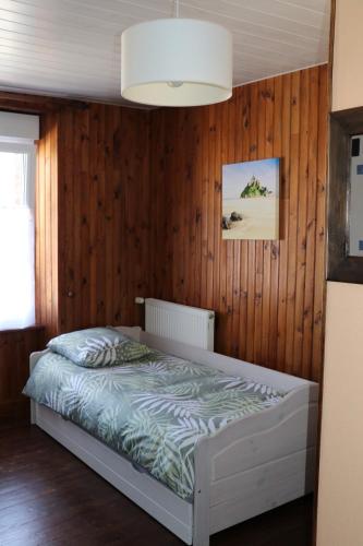 1 dormitorio con 1 cama con pared de madera en CHAMBRES D'HÔTES AU DETOUR DU MONT St Michel en Roz-sur-Couesnon