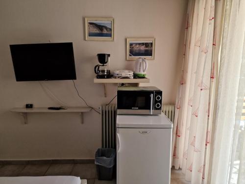a microwave on top of a refrigerator with a television at Nontas Home in Kalamitsi