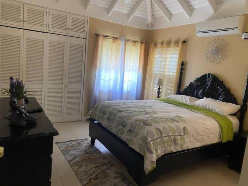 a bedroom with a bed and a table and windows at Island Style Villa in Richmond Estate Palms in Banks