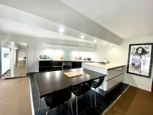 Il comprend une cuisine équipée d'un comptoir noir et d'un réfrigérateur. dans l'établissement *Victoria Plaza* Loft au cœur de Vichy, à Vichy