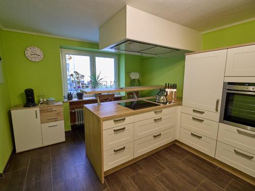 cocina con paredes verdes, armarios blancos y ventana en Ferienwohnung Grüner Flamingo, en Freisen