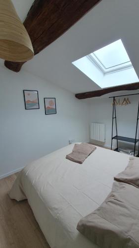 a bedroom with a large white bed and a skylight at Le Central in Lagnieu