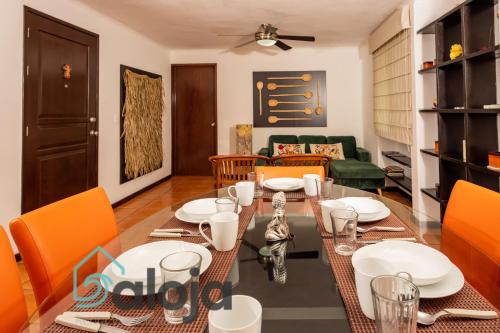 Apartamento amplio en zona ideal a 5min de WALLMART في كانكون: غرفة طعام مع طاولة وكراسي برتقالية