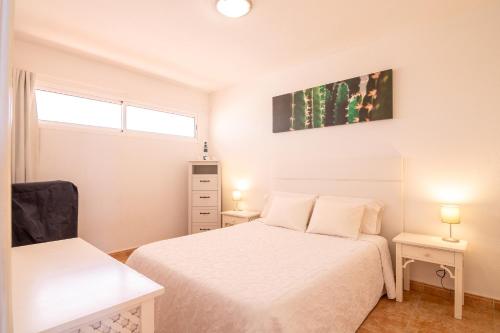 a white bedroom with two beds and two lamps at Roque del Conde Seaview in Adeje