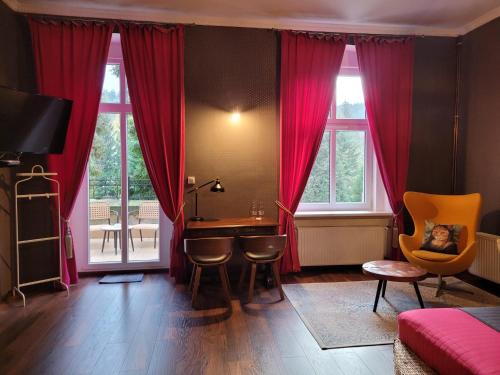 ドウゴポレ・ズドルイにあるKot Pocztowyの赤いカーテン、テーブルと椅子が備わるベッドルーム1室