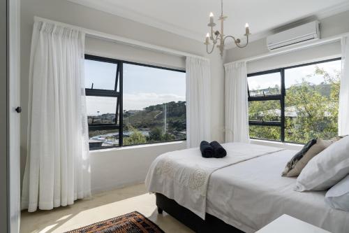 una camera con un grande letto e ampie finestre di Boskloof Eco House I a Città del Capo
