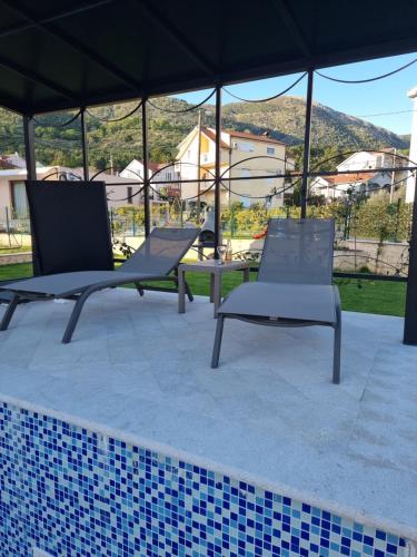 twee ligstoelen en een tafel onder een tent bij Villa with Pool & Garden apartment 2 Vuk in Tivat
