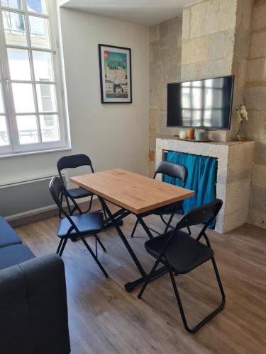 einen Tisch und Stühle in einem Zimmer mit Kamin in der Unterkunft Saumur centre : appartement entièrement rénové. in Saumur