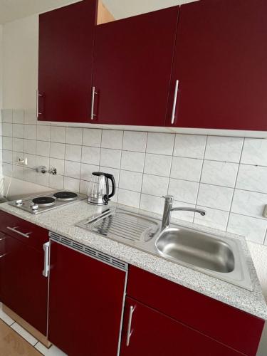 - une cuisine avec des placards rouges et un évier dans l'établissement Apartment Essen, à Essen