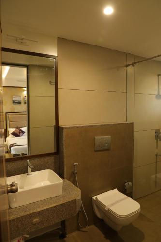 a bathroom with a sink and a toilet and a mirror at Blisss Hotel, Kolhapur in Kolhapur