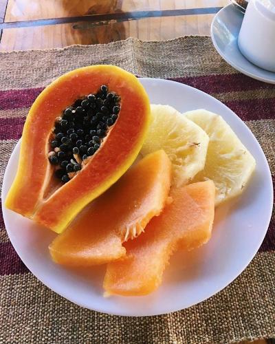 un piatto bianco con una papaya tagliata a metà con semi neri di Pousada Ello a São Miguel do Gostoso