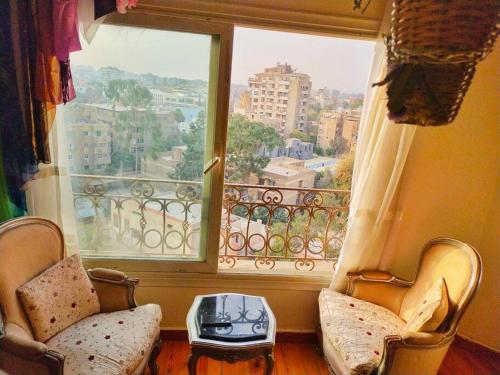 um quarto com duas cadeiras e uma grande janela em Flowered private room no Cairo