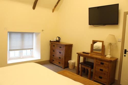 a bedroom with a bed and a dresser and a television at Palmer's Ale House in Long Sutton