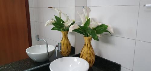 two vases with flowers on a counter next to a sink at Pousada Terra Mar Way in Barra Grande