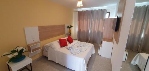 a bedroom with a bed with two red pillows on it at Pousada Terra Mar Way in Barra Grande