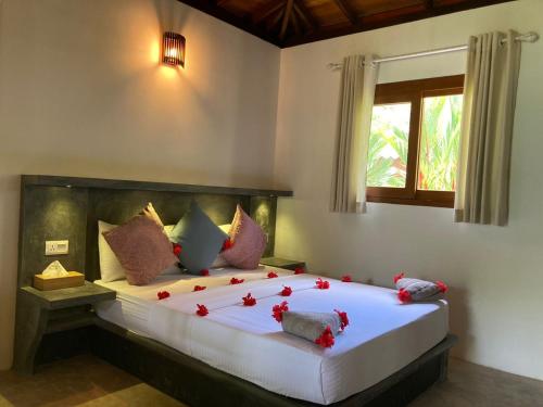 a bedroom with a large bed with red flowers on it at Avalon Village Resort in Induruwa