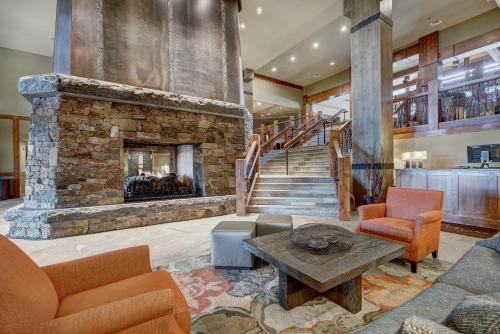 a living room with a stone fireplace and a staircase at One Ski Hill, A RockResort in Breckenridge