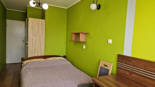 a green bedroom with a bed and a wooden table at Róża Wiatrów 2 Władysławowo in Władysławowo
