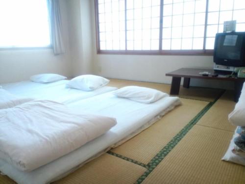 a bed with white sheets and pillows in a room at Hotel Hayashi - Vacation STAY 49819v in Beppu