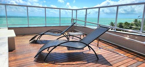 two chairs on a balcony with a view of the ocean at Paradise by Hosppedar in João Pessoa