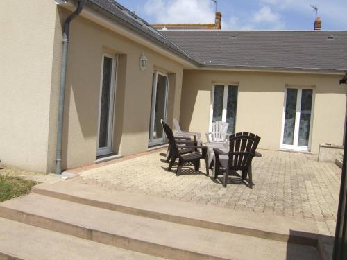 une terrasse avec quatre chaises et une table en face d'une maison dans l'établissement Ouistreham (14) Maison en bord de mer - 6 personnes, à Ouistreham