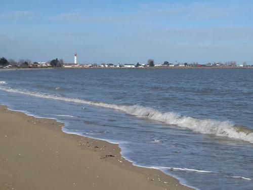 une plage avec l'océan et un phare au loin dans l'établissement Ouistreham (14) Maison en bord de mer - 6 personnes, à Ouistreham