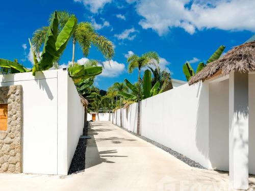 a white fence with palm trees in the background at CYAN Jasmine Pool Villa - Fisherman's Village in Bophut