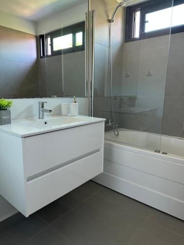 uma casa de banho branca com um lavatório e uma banheira em Leonor Seaview Apartment em Funchal