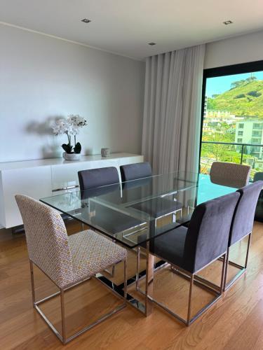 uma sala de jantar com uma mesa de vidro e cadeiras em Leonor Seaview Apartment no Funchal