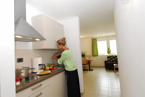 Eine Frau, die in einer Küche steht und Essen zubereitet. in der Unterkunft Residence Remi in Schnals