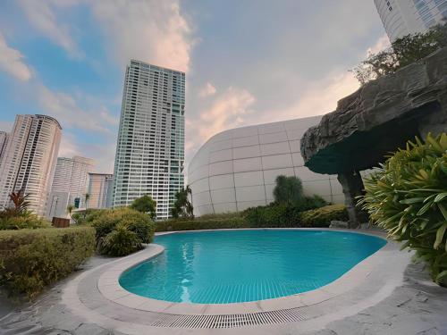 a swimming pool in front of a building with tall buildings at Aveline Suites Executive City View ACQUA Private Residences near Rockwell Makati in Manila