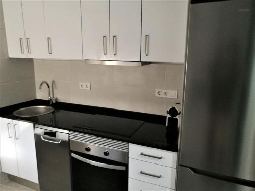 una cocina con nevera de acero inoxidable y armarios blancos en Apartamento céntrico en Palamós, en Palamós