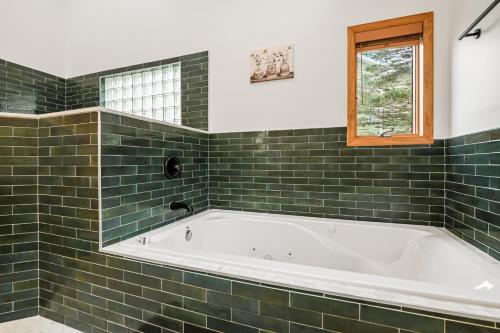 uma casa de banho com azulejos verdes, uma banheira e uma janela. em 226 E Shore Dr em East Stroudsburg