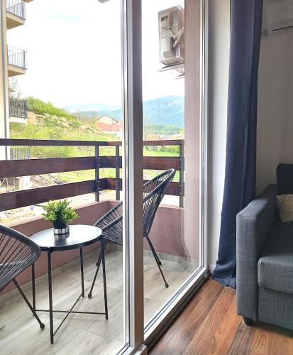 a balcony with a table and a chair and a window at Apartmani ZAT in Soko Banja