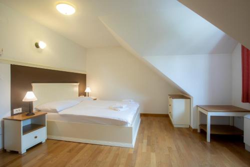 een slaapkamer met een groot wit bed en een tafel bij Lakeside Apartments Bled in Bled