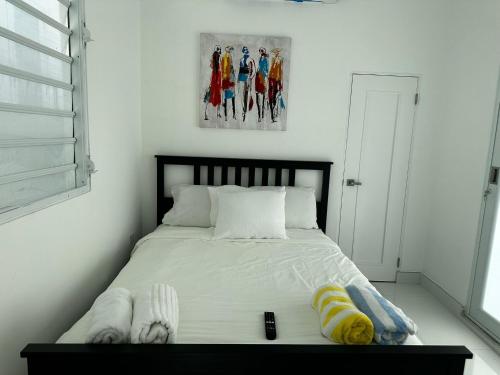 sypialnia z łóżkiem z białą pościelą i zdjęciem na ścianie w obiekcie Gorgeous 1-Bedroom Beachside Suite w mieście San Juan