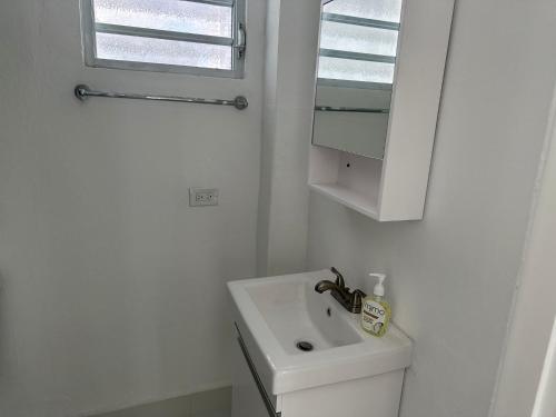 W białej łazience znajduje się umywalka i lustro. w obiekcie Gorgeous 1-Bedroom Beachside Suite w mieście San Juan