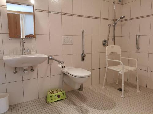 a bathroom with a toilet and a sink and a chair at Zauscherhof in Wildermieming