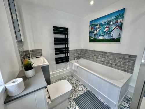 a white bathroom with a tub and a toilet at Paintworks View by MyCityHaven in Bristol