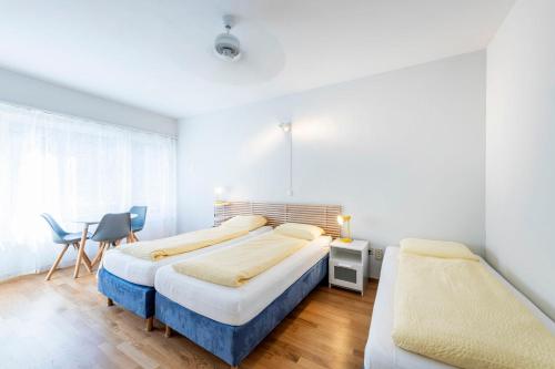 a bedroom with two beds and a table and chairs at Hotel Atlantico self check-in in Lugano